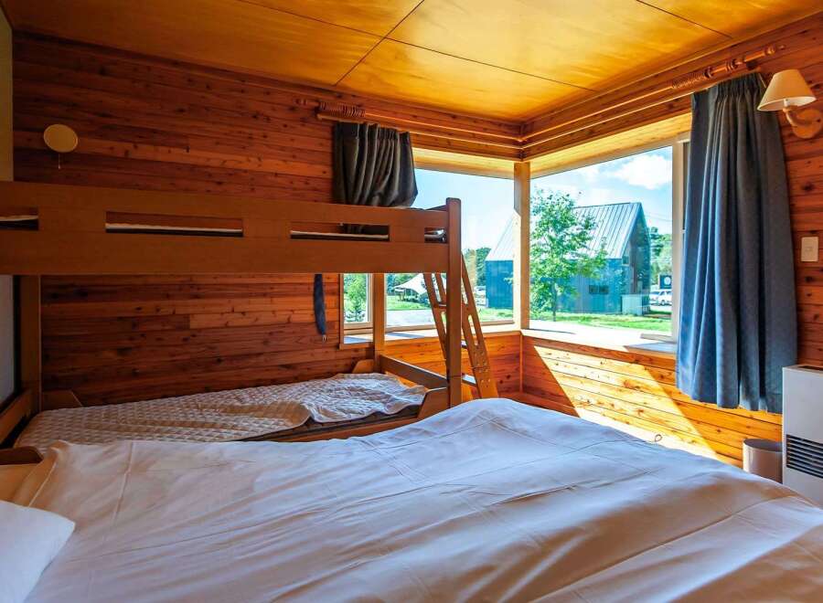 Cozy cabin room with a bunk bed and a large comfortable bed, perfect for families.