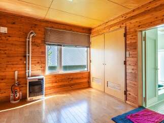 This charming wooden room features a spacious layout with a large window, providing ample natural light.