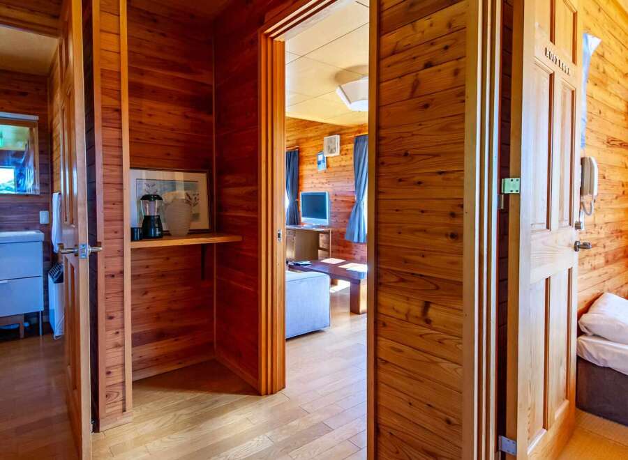 Cozy wooden cabin with a bathroom, living area, and bedroom.