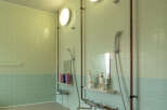 This clean and modern bathroom features two shower stalls with exposed copper pipes, sleek chrome fixtures, and built-in shelves for toiletries.