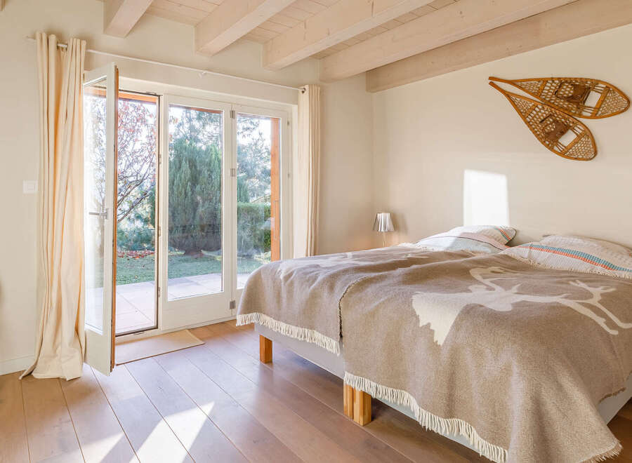Cozy bedroom with a view! This charming space features a comfortable bed with a unique blanket and a bright, airy feel thanks to the large windows.