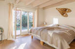 Cozy bedroom with a view! This charming space features a comfortable bed with a unique blanket and a bright, airy feel thanks to the large windows.