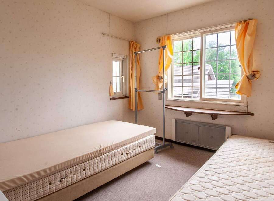 Cozy bedroom with two single beds, a window with natural light, and a clothes rack.