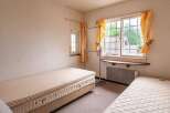Cozy bedroom with two single beds, a window with natural light, and a clothes rack.