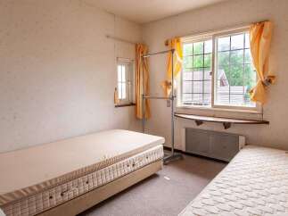 Cozy bedroom with two single beds, a window with natural light, and a clothes rack.