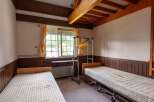 Cozy twin bedroom with wood-paneled walls and ceiling beams.