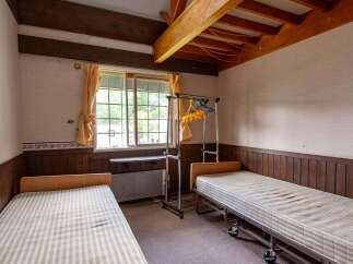 Cozy twin bedroom with wood-paneled walls and ceiling beams.