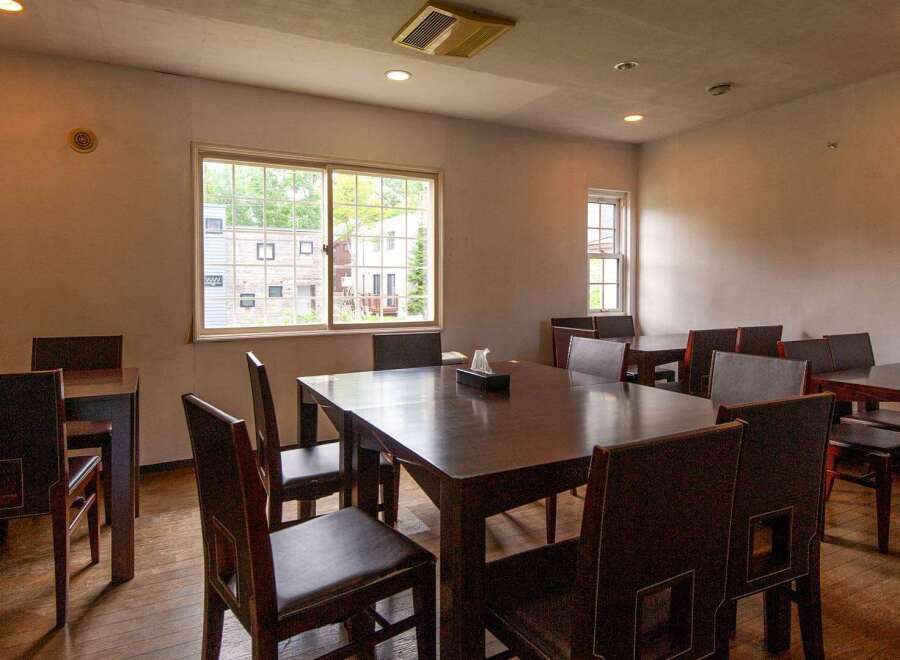 A cozy restaurant interior with multiple dark brown wooden tables and chairs, offering a comfortable dining experience.