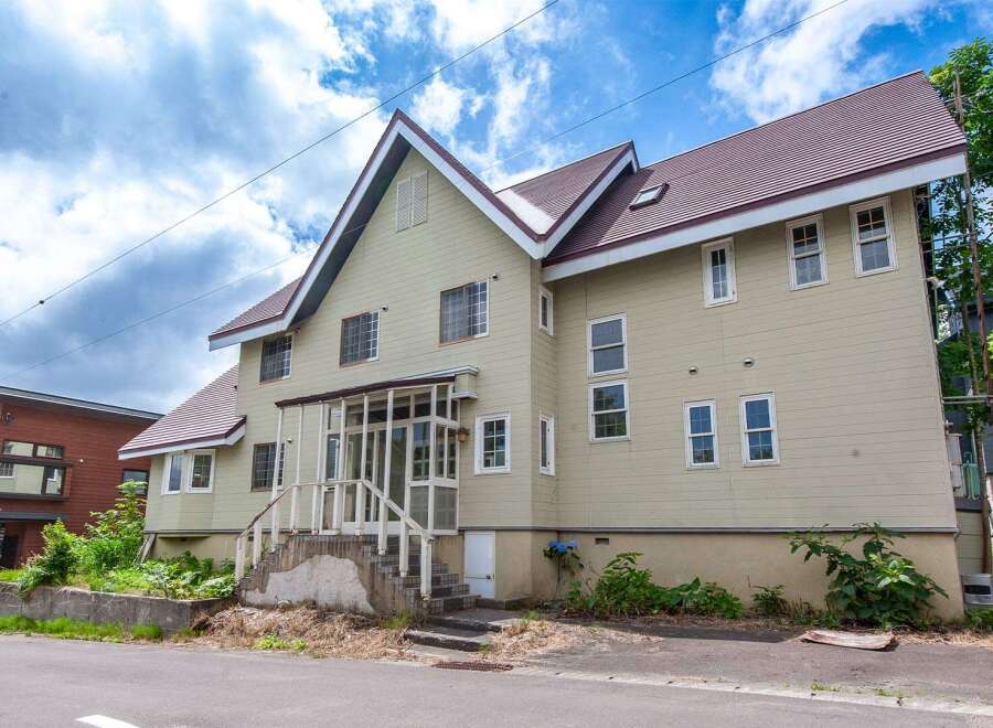 This charming two-story house boasts a unique A-frame design, complemented by a reddish-brown roof.