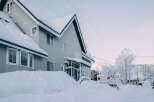 This charming snow-covered house boasts a spacious design with multiple windows, offering ample natural light.