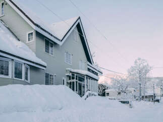 This charming snow-covered house boasts a spacious design with multiple windows, offering ample natural light.