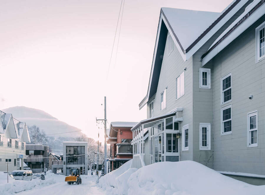 Charming snow-covered houses line a quiet street, showcasing a blend of architectural styles.