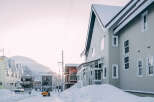 Charming snow-covered houses line a quiet street, showcasing a blend of architectural styles.