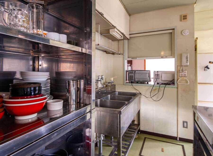 This commercial kitchen boasts ample storage with stainless steel shelving units stocked with dishes, glassware, and kitchen tools.