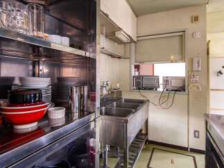 This commercial kitchen boasts ample storage with stainless steel shelving units stocked with dishes, glassware, and kitchen tools.