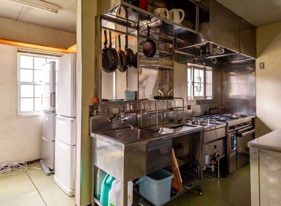 This commercial kitchen boasts stainless steel countertops, a large sink, and ample storage.