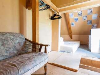 Cozy attic room with a floral patterned couch, wooden closet, and a built-in bed.