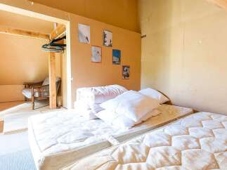 Cozy attic bedroom with twin mattresses, ample pillows, and built-in closet.
