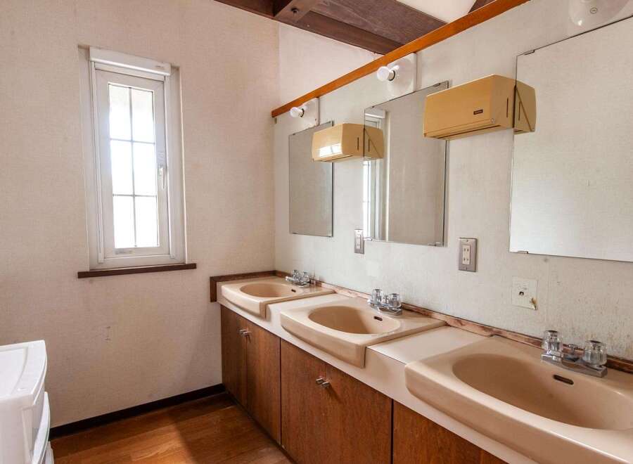 This property features a retro-style bathroom with three sinks, each with its own mirror and vintage faucets.