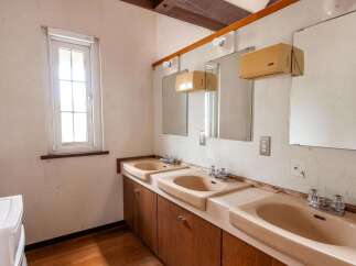 This property features a retro-style bathroom with three sinks, each with its own mirror and vintage faucets.