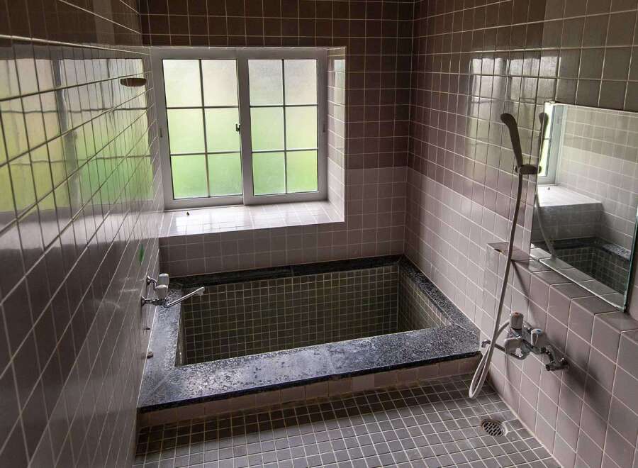 This charming bathroom boasts a vintage aesthetic with its dark gray tiled walls and flooring.