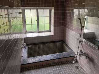 This charming bathroom boasts a vintage aesthetic with its dark gray tiled walls and flooring.