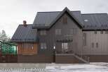 This stunning property boasts a modern exterior with a dark metal roof and siding, complemented by rich wood accents.