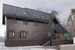 This stunning property boasts a modern exterior with dark metal siding and a striking dark brown stone base.