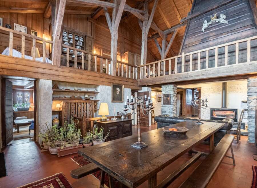 This stunning chalet boasts a magnificent open-plan living area with exposed wooden beams and a grand dining table, perfect for entertaining.