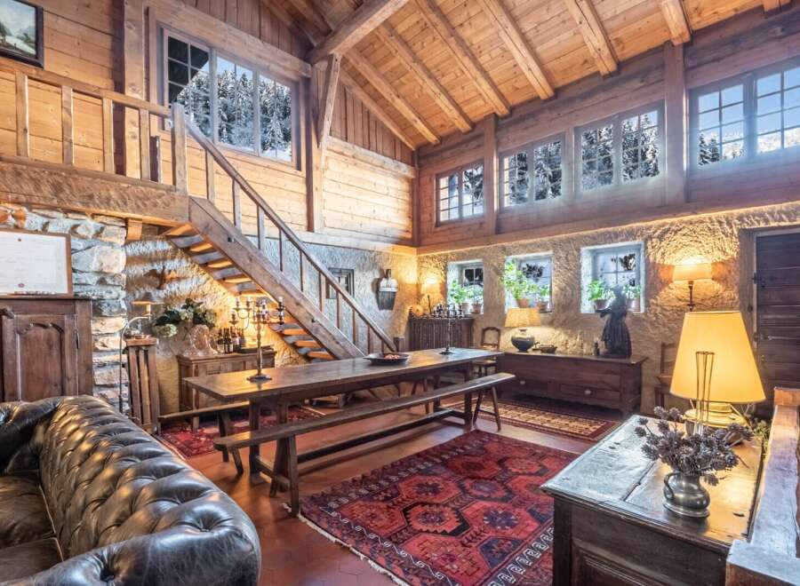 This stunning chalet boasts a spacious open-plan living area with exposed wooden beams and large windows offering breathtaking views.