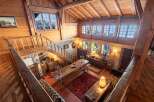 This stunning chalet boasts a spacious open-plan living area with exposed wooden beams and large windows offering breathtaking views of the snowy landscape.