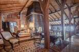 Rustic charm meets modern comfort in this unique chalet featuring exposed wooden beams, a cozy sitting area with antique furniture, and a stunning stone fireplace.