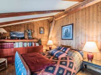 Cozy chalet bedroom with wooden walls and exposed beams.