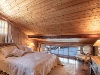 Cozy chalet bedroom with wooden walls and ceiling, featuring a comfortable queen-size bed and large windows offering stunning views.
