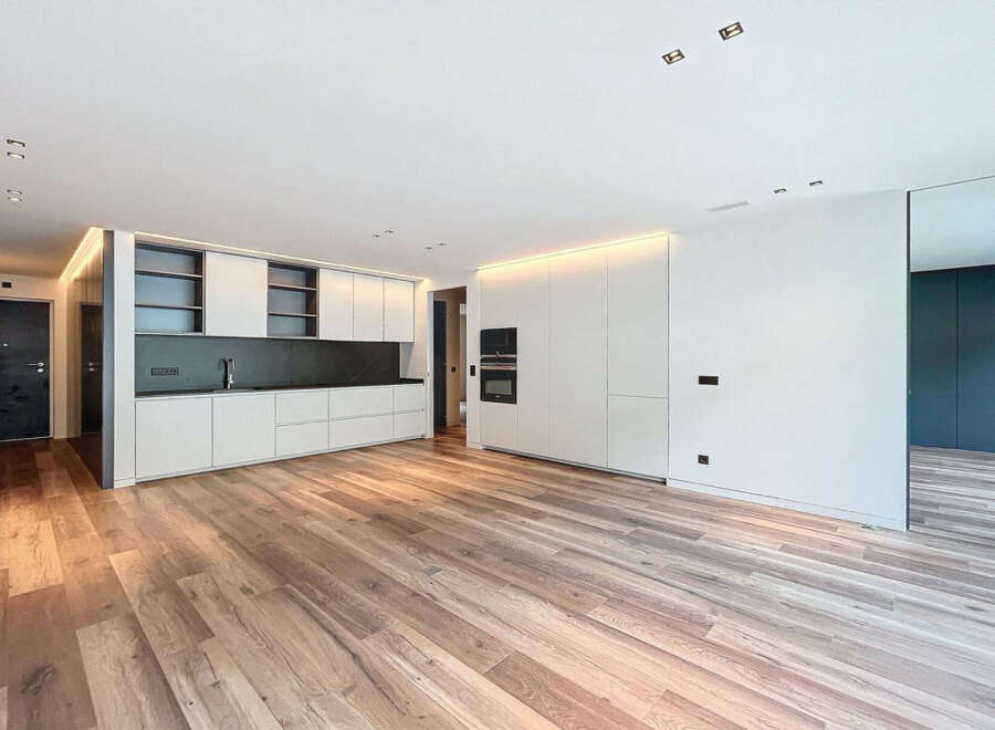 Stunning open-plan living space with sleek, modern kitchen and high-end wood flooring.