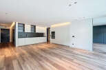 Stunning open-plan living space with sleek, modern kitchen and high-end wood flooring.