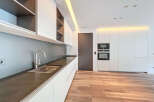 Modern kitchen with sleek white cabinets, dark countertops, and integrated appliances.