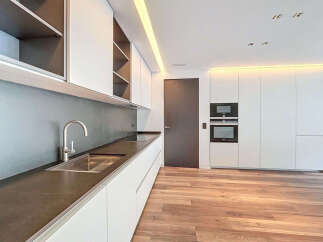 Modern kitchen with sleek white cabinets, dark countertops, and integrated appliances.