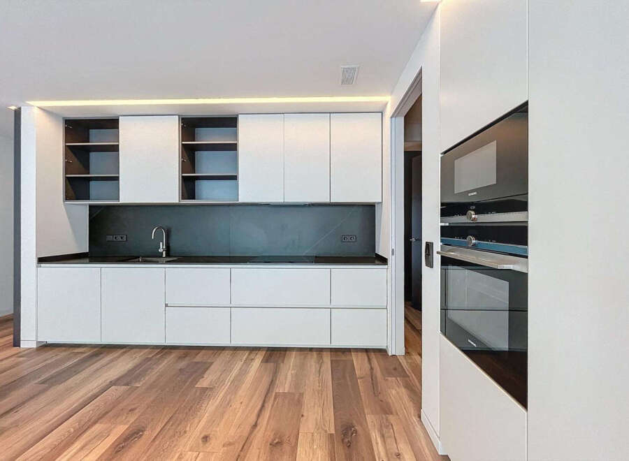 Modern kitchen with sleek white cabinets and dark countertops.