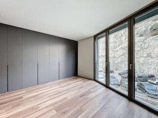 Modern apartment boasting sleek dark gray built-in wardrobes and stunning floor-to-ceiling windows offering breathtaking views.