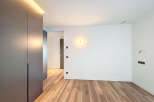 This stunning property boasts a modern, minimalist design with sleek dark gray built-in wardrobes and light oak wood flooring.