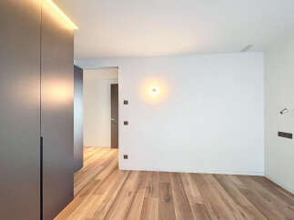 This stunning property boasts a modern, minimalist design with sleek dark gray built-in wardrobes and light oak wood flooring.