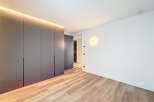 Modern apartment boasts sleek built-in wardrobes and light oak wood flooring.