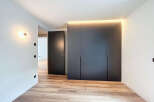 Modern bedroom with built-in wardrobes and wooden flooring.
