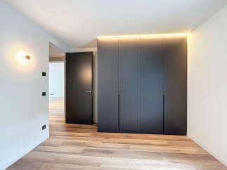Modern bedroom with built-in wardrobes and wooden flooring.
