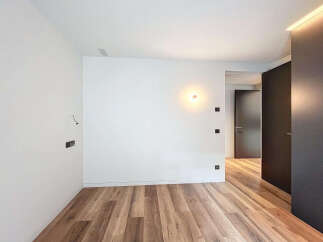 This stunning property boasts a spacious, bright bedroom with sleek hardwood floors and modern wall sconces.