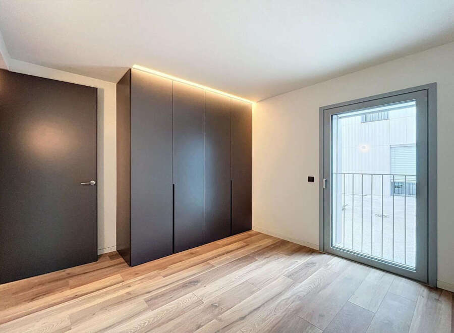 Modern apartment boasting sleek built-in wardrobes and light oak flooring.