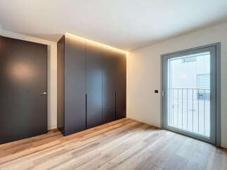 Modern apartment boasting sleek built-in wardrobes and light oak flooring.