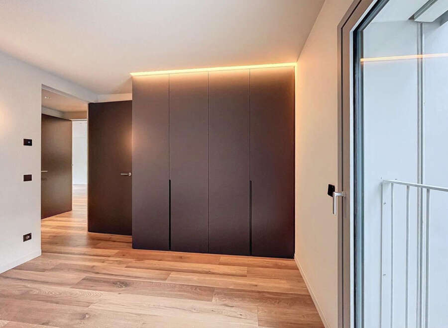 Modern apartment boasts sleek built-in wardrobes with integrated lighting, enhancing the minimalist aesthetic.