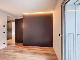 Modern apartment boasts sleek built-in wardrobes with integrated lighting, enhancing the minimalist aesthetic.